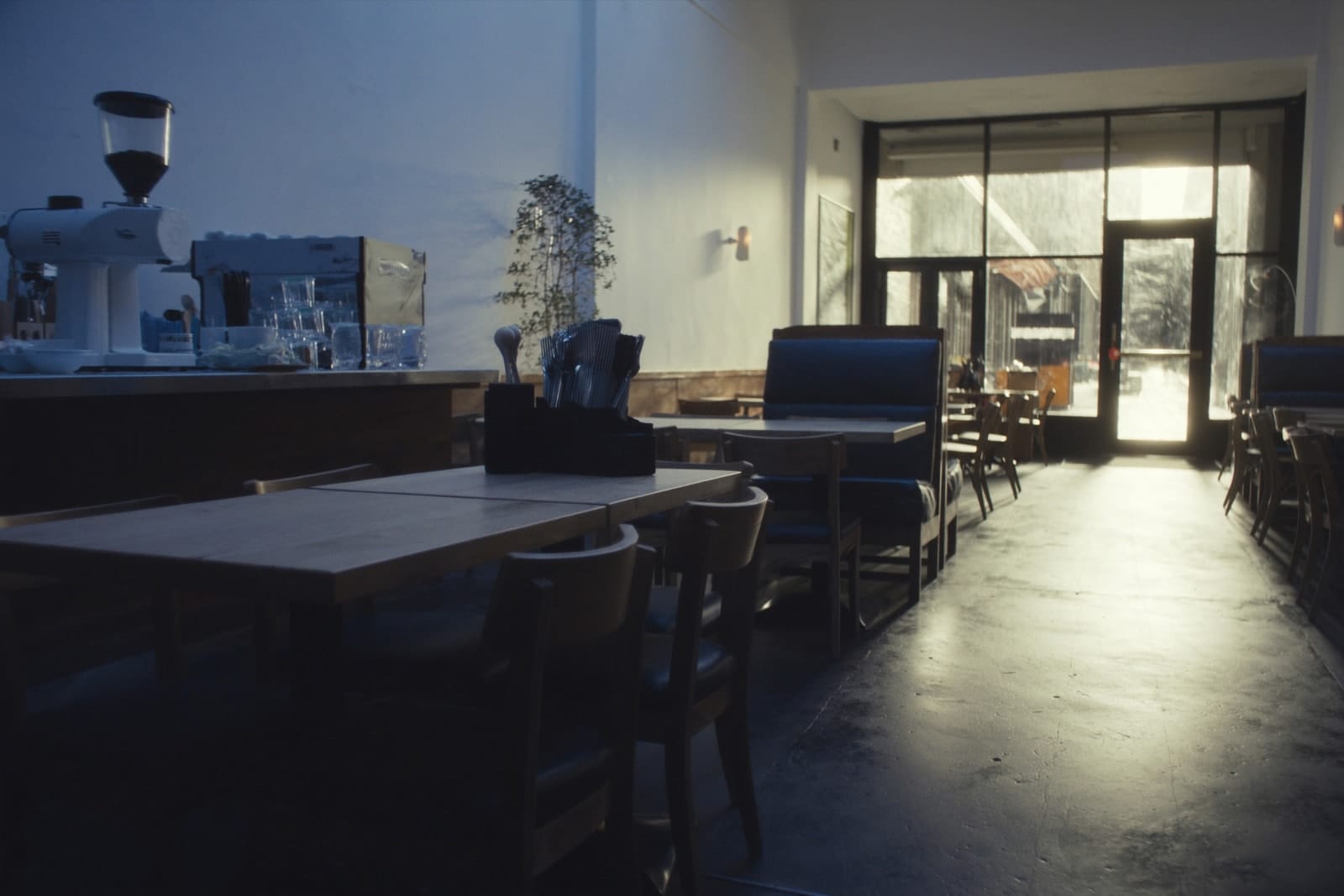 An empty cafe before opening with wiped timber tables, neat chairs and a clean espresso counter.